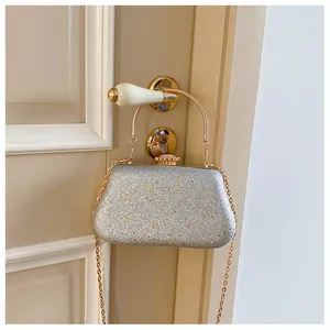 Detail of silver sequined evening clutch with gold handle hanging on door
