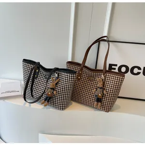 Detail of houndstooth tote bags with plush rabbit charm and vegan leather straps