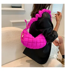 Detail of neon pink quilted puff shoulder bag with wavy strap on a female model