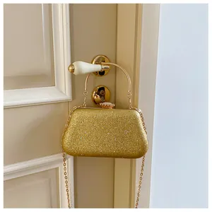 Detail of glitter evening bag in gold with round handle hanging on a vintage door handle