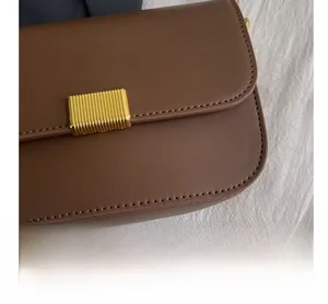 Detailed view of dark brown leather texture and golden striped metal lock on square bag
