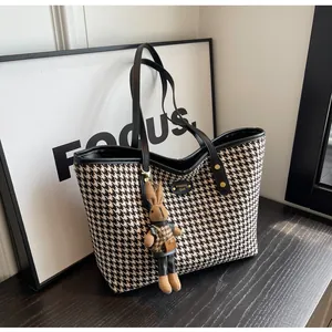 Close-up of black and white houndstooth tote bag with a cute rabbit plush pendant detail