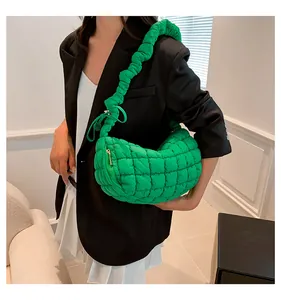 Close-up of bright green quilted puffer bag with pleated shoulder strap and metal zipper