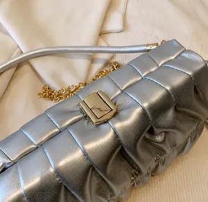 Detail der silbernen Lederhandtasche mit goldenem Verschluss und Ketten-Schulterriemen