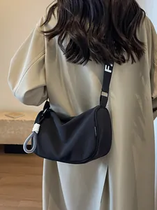 Fashionable black nylon crescent crossbody bag with broad logo strap and rope charm