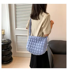 Gewatteerde lichtblauwe puffy schoudertas gecombineerd met beige blazer en zwarte jurk