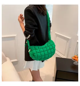 Close-up of green quilted nylon dumpling bag featuring gold zipper and wide strap