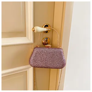 Detail of glitter evening bag with golden round handle and pearl clasp on a door