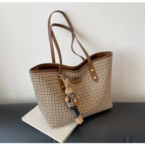 Detailed shot of houndstooth tote bag featuring a gold metal nameplate and bunny charm