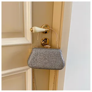 Detail of glitter evening clutch bag with metal handle and pearl clasp on a door handle