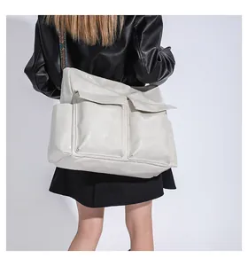 Detail of a large cream tote bag featuring front flap pockets and a colorful woven strap