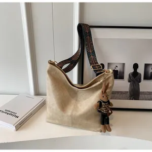 Detail view of beige hobo tote bag with ethnic embroidery strap and cute bunny charm