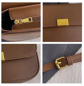 Detail view of brown leather bag with gold metal zipper, lock and adjustable shoulder strap