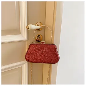 Detailed close-up of the red sequined evening bag with a gold metal handle and chain
