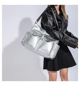 Detail of silver metallic tote bag featuring pleated texture and ethnic woven strap