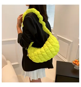 Detail of neon yellow quilted padded shoulder bag with ruched strap on model