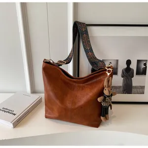 Brown vintage tote bag detail showing ethnic patterned strap and a cute rabbit pendant