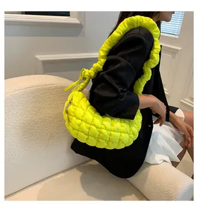 Detail of neon green quilted hobo bag featuring ruched shoulder strap and metallic zipper