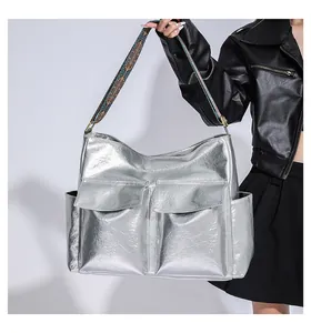 Detail of silver metallic tote bag featuring geometric patterned wide strap and large front pockets