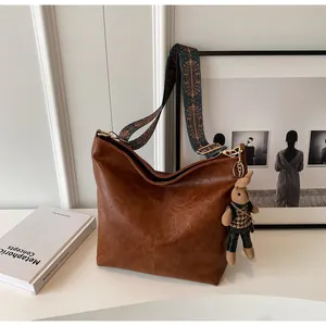 Detail of vintage brown tote bag with ethnic embroidered strap and cute rabbit pendant
