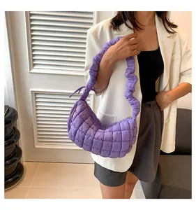 Detailed close-up of a quilted purple puffy handbag with pleated handle on a model