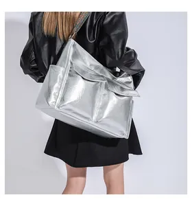 Detail of silver metallic tote bag featuring textured finish and embroidered strap