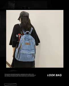 Detailed view of large denim backpack showing durable texture and brown leather brand logo