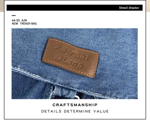 Detailed shot of brown leather logo patch on blue denim crossbody bag craftsmanship