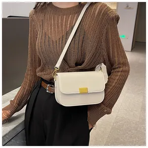 Detail shot of a cream white minimalist crossbody bag with a golden square metal clasp