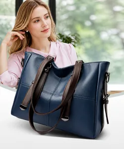 Elegante große dunkelblaue Ledertasche mit braunen Griffen, getragen von einem Modell