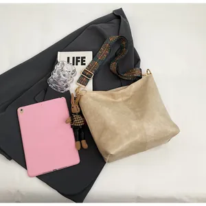 Detailed view of beige faux leather tote bag with printed wide strap and rabbit charm accessory