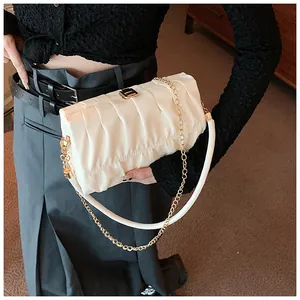 Detail der beigen Falten-Schultertasche mit goldener Kette und metallischem Druckverschluss