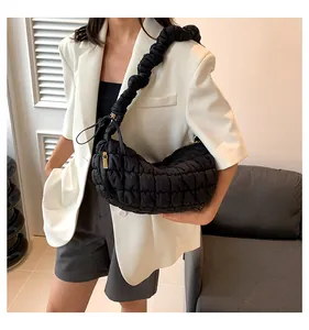 Detail of black quilted puffer bag featuring pleated shoulder strap and gold zipper