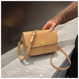 Detail of khaki leather crossbody bag featuring a golden rectangular metal buckle closure