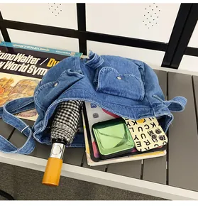 Detail view of large denim messenger bag interior holding tablet, phone and umbrella