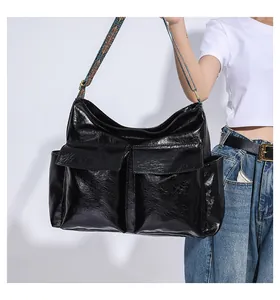 Detail of a large black vintage tote bag with glossy finish and ethnic style shoulder strap