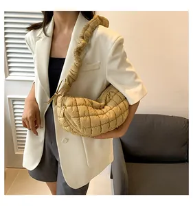 Close-up of khaki quilted puffer shoulder bag with ruched strap on a model shoulder