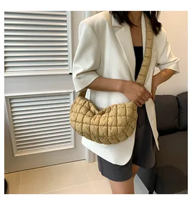 Close-up of quilted beige hobo bag on model in a stylish white blazer outfit