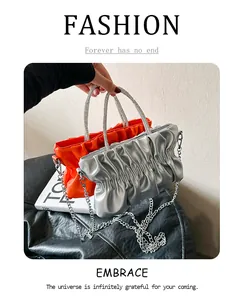Detailed shot of orange and silver pleated cloud bags with sparkling rhinestone handles