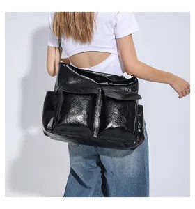 Detail of black glossy faux leather tote bag showing large front flap pockets and texture