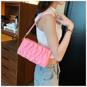 Nahaufnahme der rosa gefalteten PU-Leder-Schultertasche am Modell in eleganter Umgebung