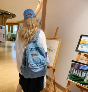 Lifestyle-Foto eines Modells mit hellblauem Denim-Rucksack in einem hellen Kunstatelier