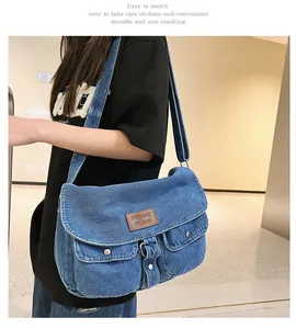 Macro shot of washed blue denim texture and brown leather logo tag on the crossbody bag
