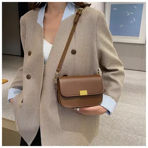 Detail of dark brown leather crossbody bag with golden rectangular clasp and fine strap