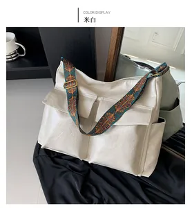 Detail of off-white tote bag featuring ethnic style wide strap and front pockets