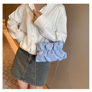 Gros plan du sac nuage plissé bleu clair avec chaîne argentée sur modèle en chemise