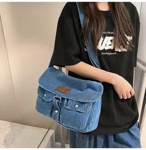 Blue denim crossbody bag detail featuring dual front pockets and brown leather logo patch