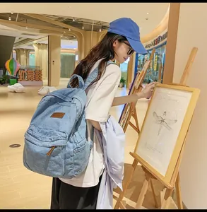Detailansicht eines hellblauen Denim-Rucksacks mit braunem Lederpatch und Fronttasche