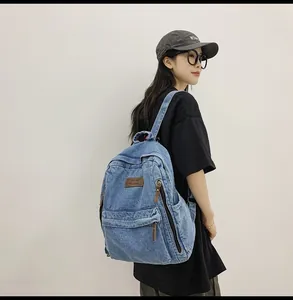 Detail of vintage blue denim backpack featuring side zippers and brown leather patch