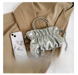 Detail of silver pleated cloud bag with sparkling rhinestone handles and chain strap